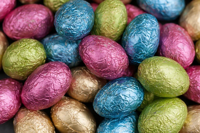Foil-wrapped chocolate easter eggs piled together in a heap