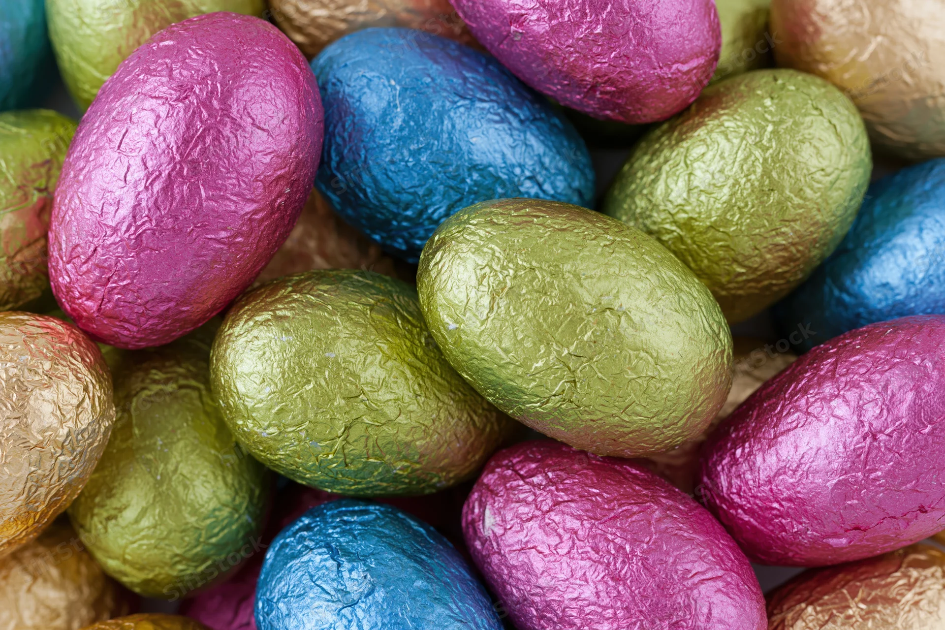 Foil-wrapped chocolate easter eggs piled together in closeup view