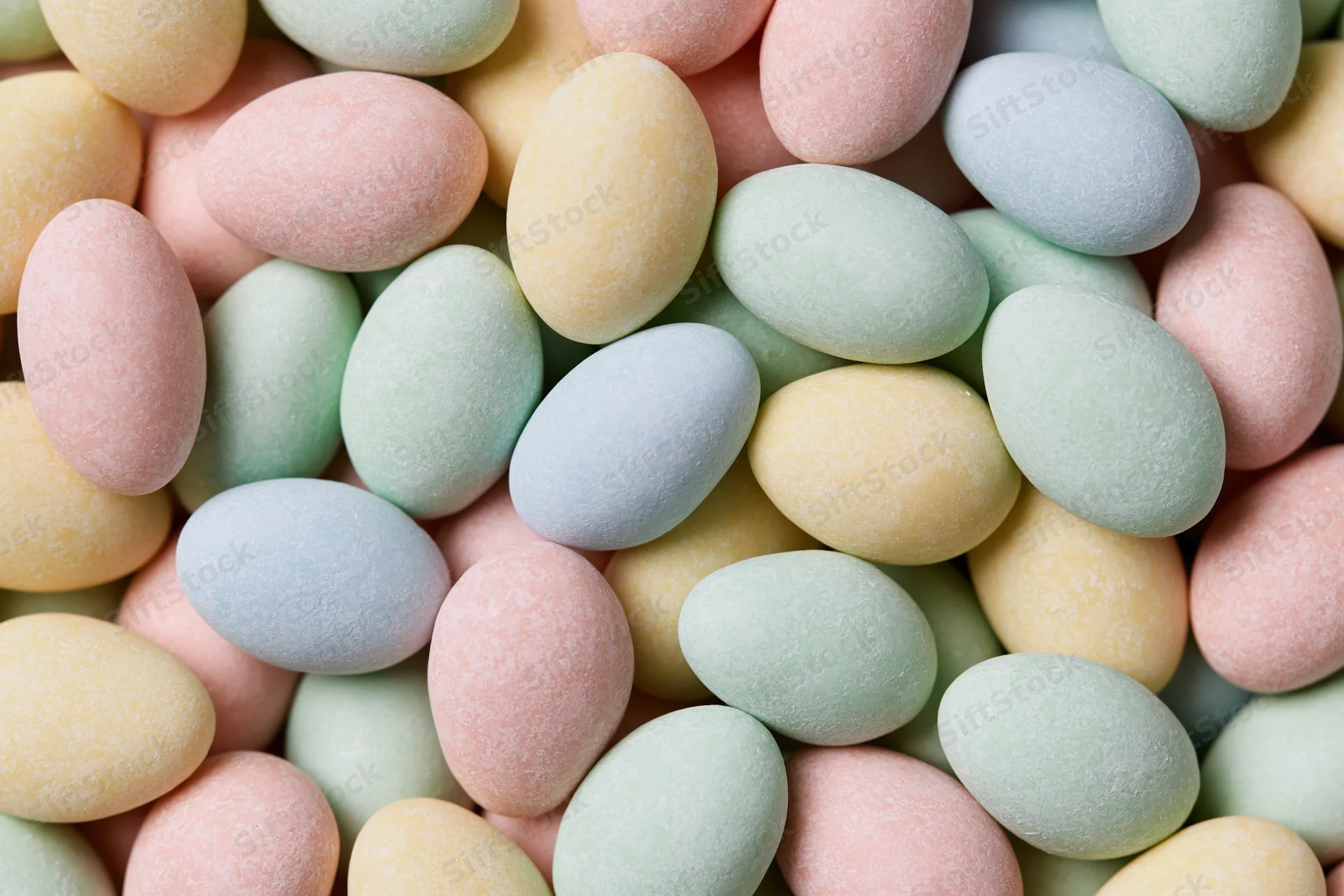 Pastel candy-coated chocolate eggs filling the frame in a close-up still life arrangement