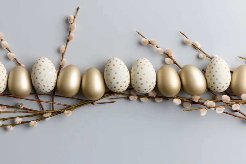 Easter eggs and pussy willow branches arranged in a flat lay on a light gray surface