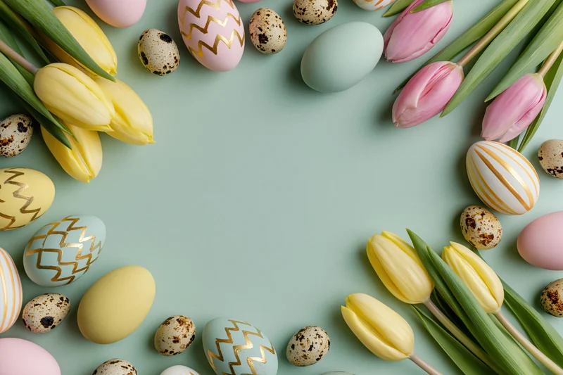 Easter eggs and tulips arranged in a flat lay on a mint background with copyspace