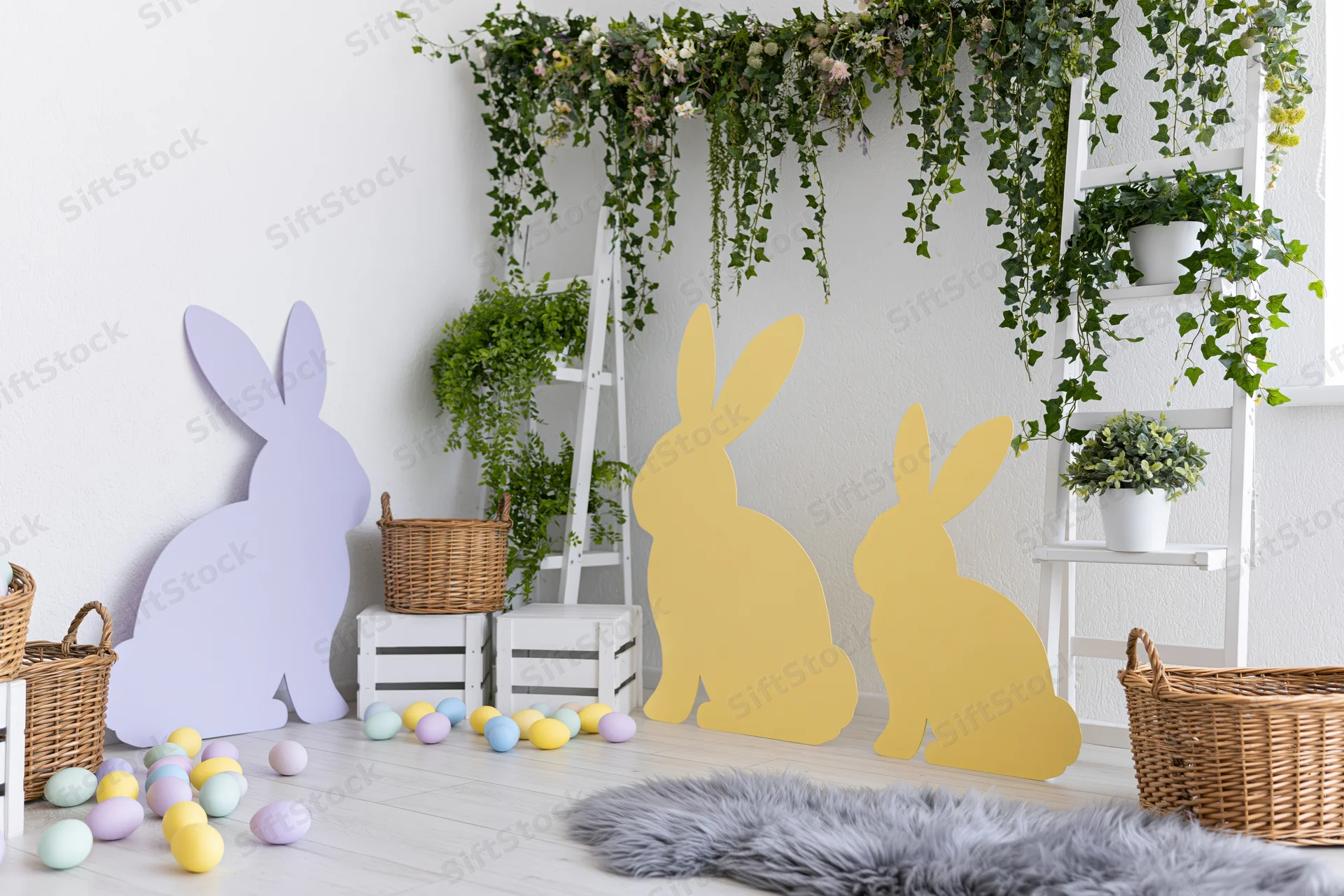 Easter photo booth setup with bunny silhouettes, colorful eggs, wicker baskets and greenery in a bright white studio