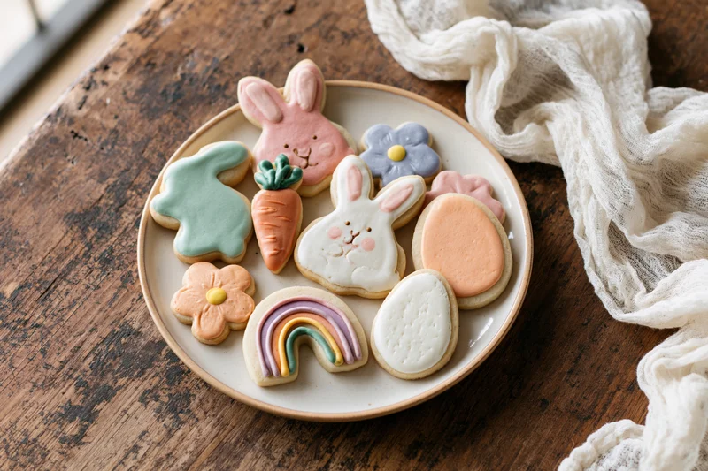 Easter sugar cookies decorated with royal icing arranged on a ceramic plate on a wooden table