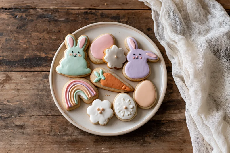 Easter sugar cookies decorated with royal icing arranged on a ceramic plate on a wooden table