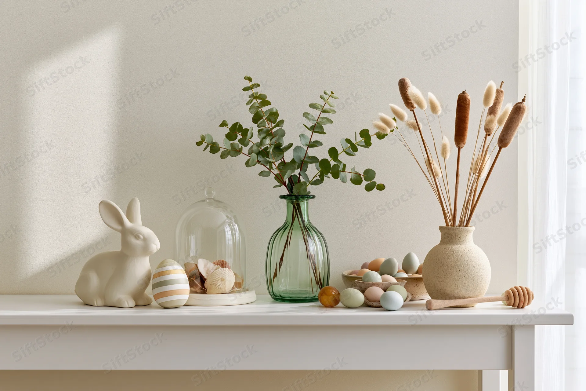 Easter decoration arranged on a white console table with ceramic bunny, vases, eggs and dried plants