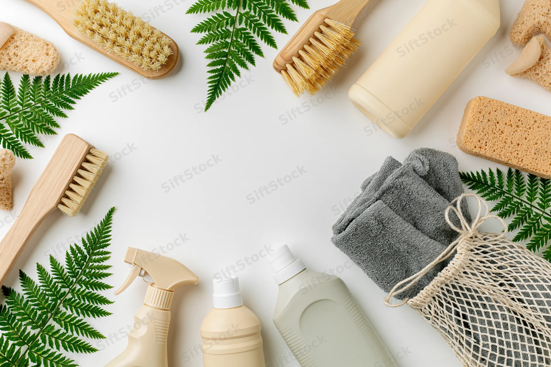 Eco-friendly cleaning supplies arranged in a flat lay frame on white background with fern leaves and copyspace