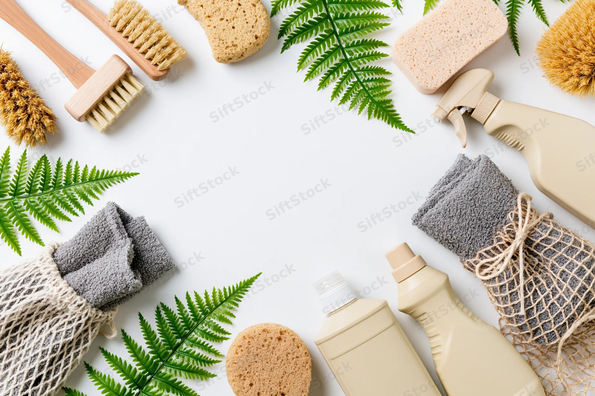Eco-friendly cleaning supplies arranged in a flat lay frame on white background with fern leaves and copyspace