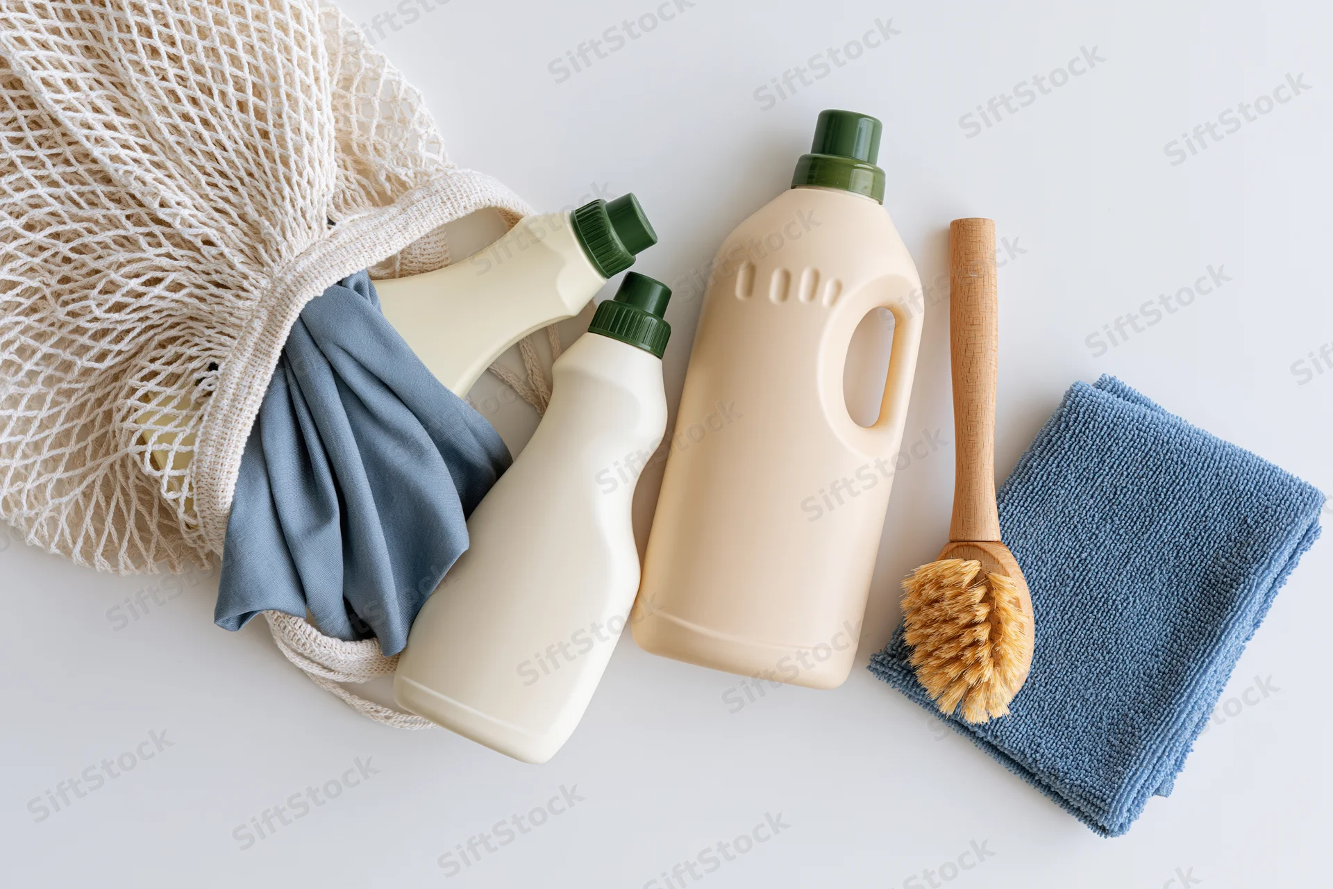 Eco-friendly cleaning supplies spilling from a white mesh bag on a white surface