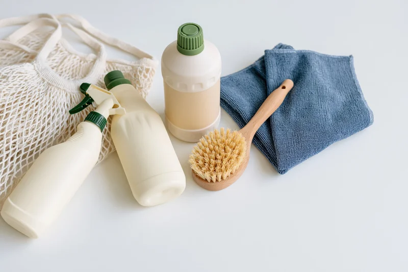 Eco-friendly cleaning supplies arranged with mesh bag and cloth on white surface