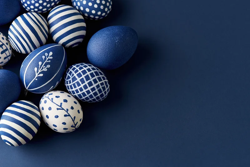 Decorated easter eggs arranged in a loose cluster on a dark blue background with copyspace