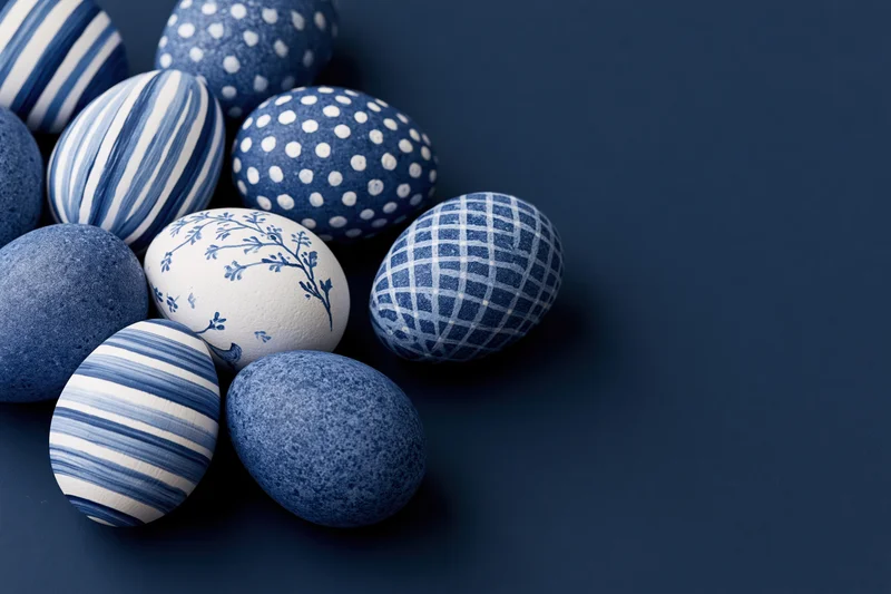 Decorated easter eggs arranged loosely in the lower-left corner on a dark blue surface with copyspace