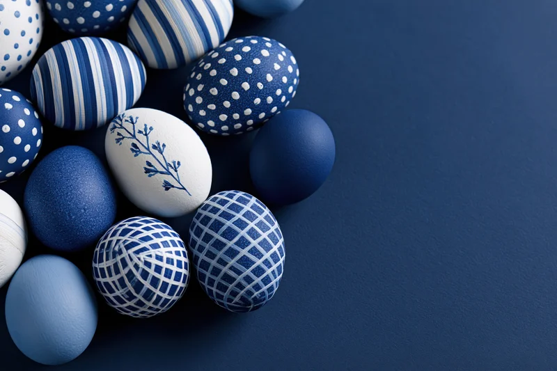 Decorated easter eggs arranged loosely on a blue surface with copyspace
