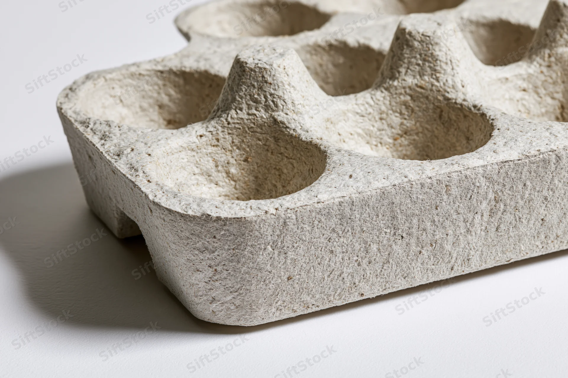 Empty recycled cardboard egg carton tray lying flat on white surface