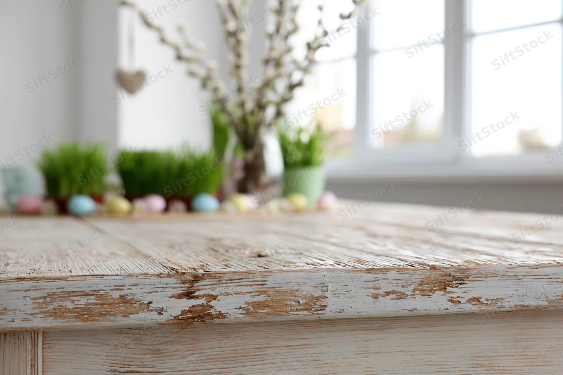 Empty rustic wooden table surface in foreground with spring easter decorations in background