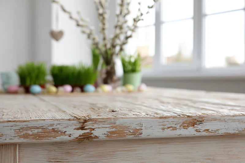 Empty rustic wooden table surface in foreground with spring easter decorations in background