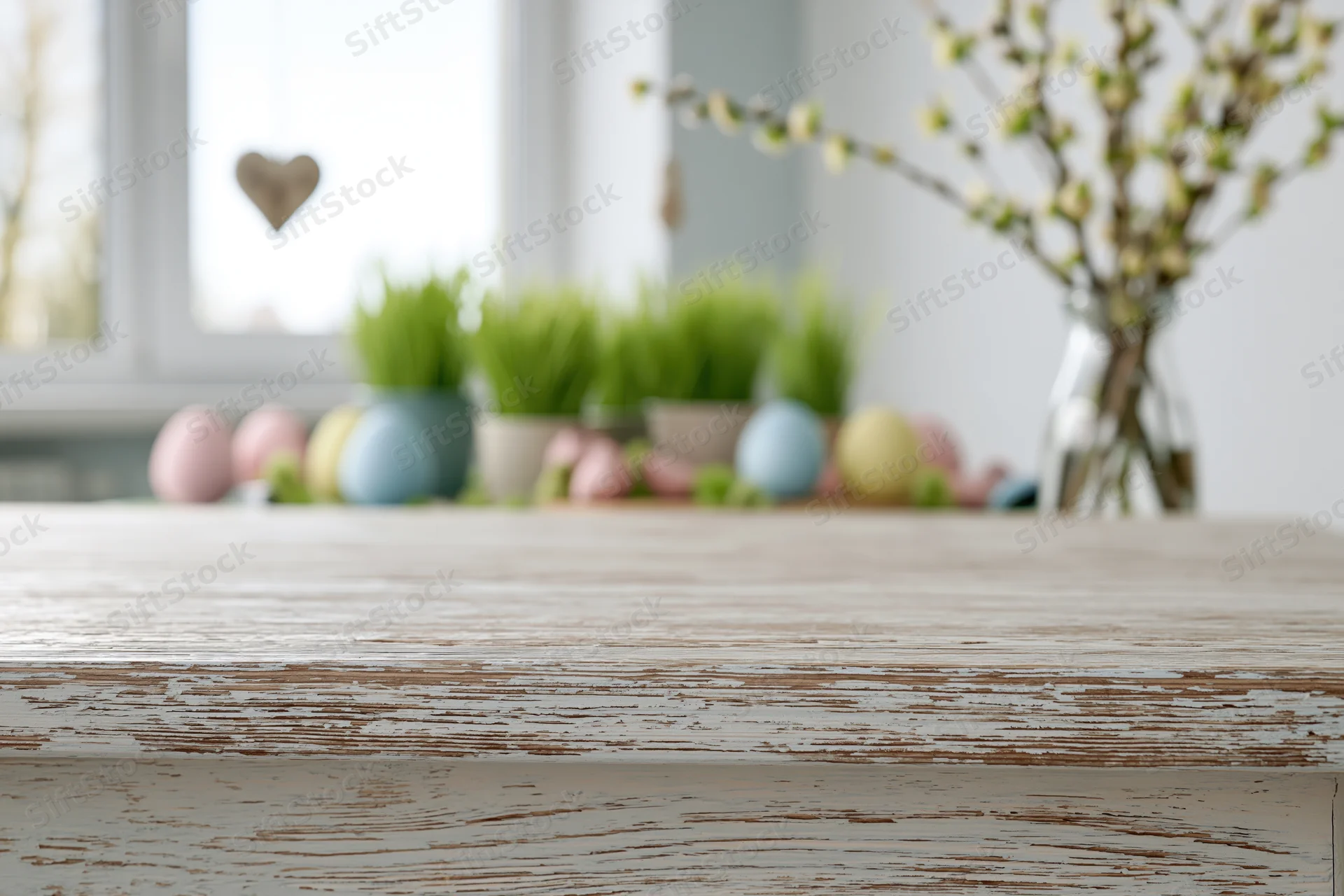 Rustic wooden table surface in foreground with easter decorations and spring plants in background near window