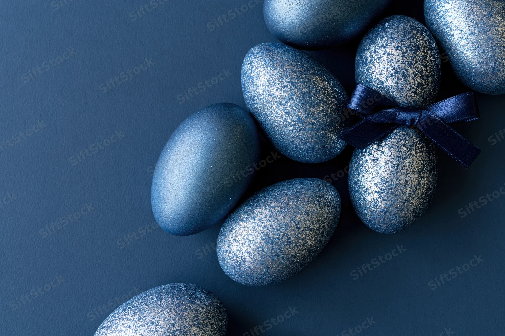 Decorated blue easter eggs arranged along the right edge on a dark surface with copyspace