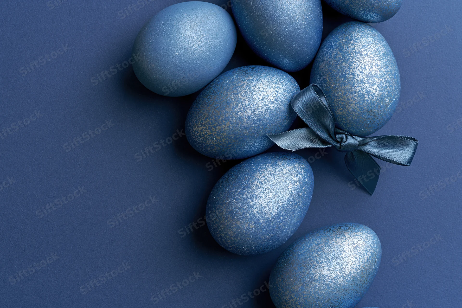 Blue decorated easter eggs arranged along the right edge with a ribbon bow on a solid background