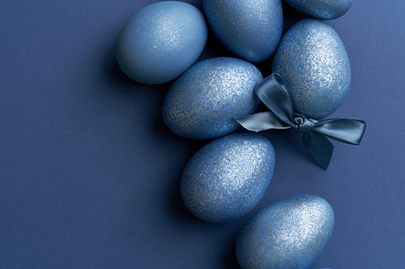 Blue decorated easter eggs arranged along the right edge with a ribbon bow on a solid background