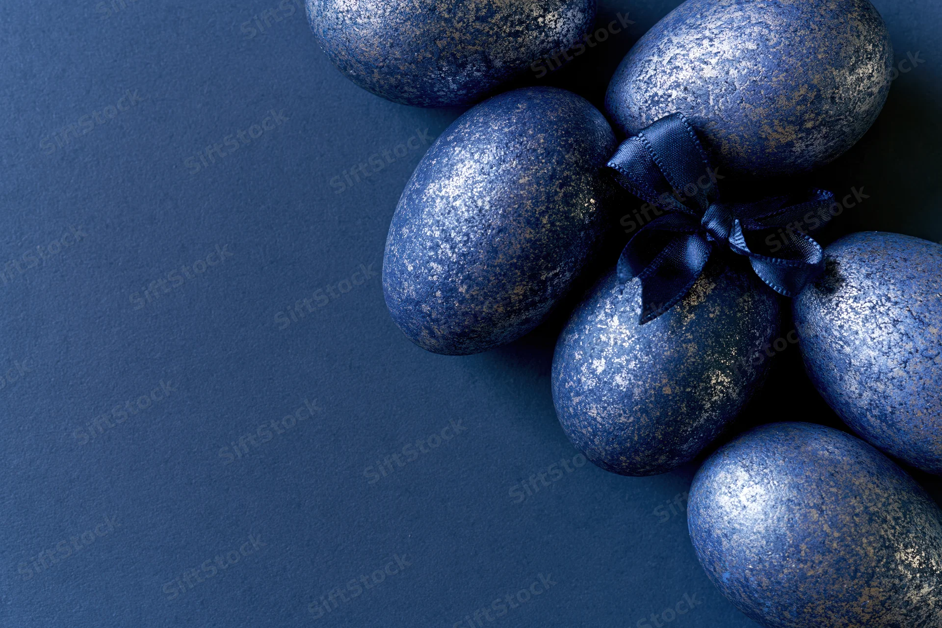 Decorated easter eggs arranged along the right edge on a dark blue surface with copyspace