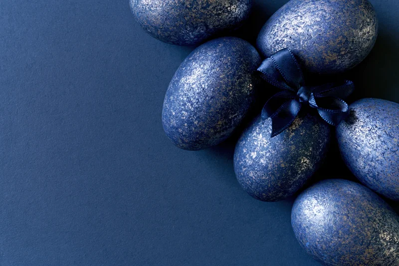 Decorated easter eggs arranged along the right edge on a dark blue surface with copyspace