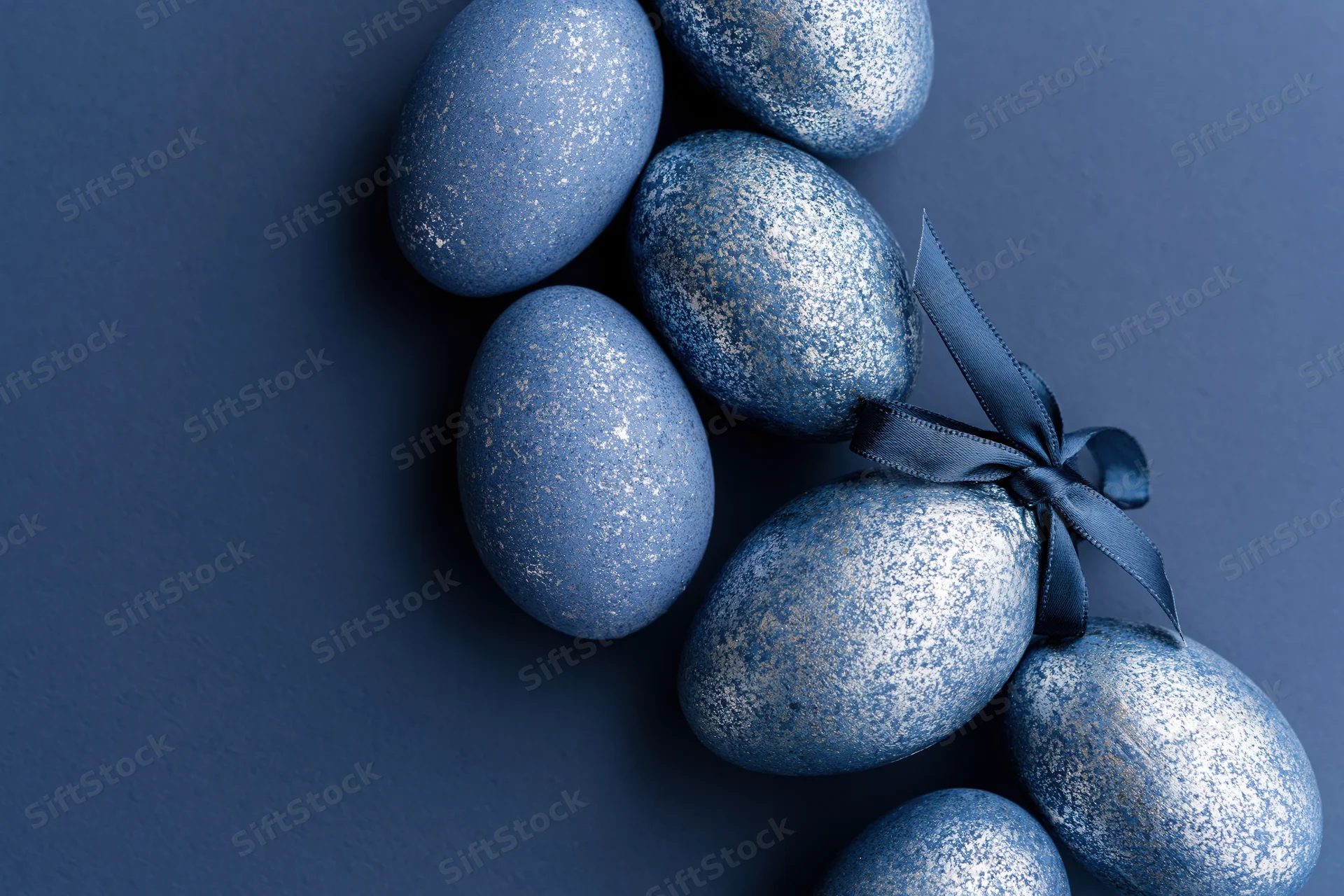 Decorated blue glitter easter eggs arranged along the right edge on dark background with copyspace