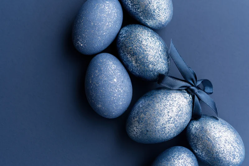 Decorated blue glitter easter eggs arranged along the right edge on dark background with copyspace