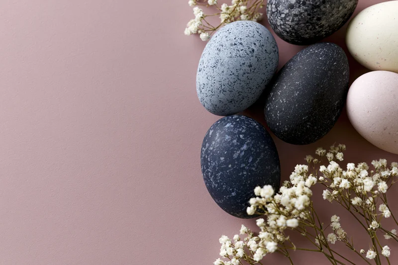 Marble-painted easter eggs arranged with baby's-breath flowers on a pink surface