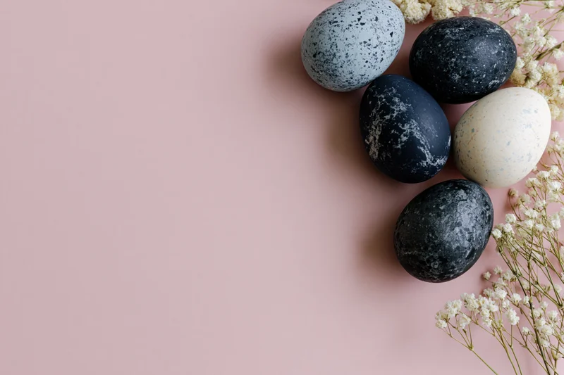 Five marble-painted easter eggs arranged with baby's-breath flowers on a pink background