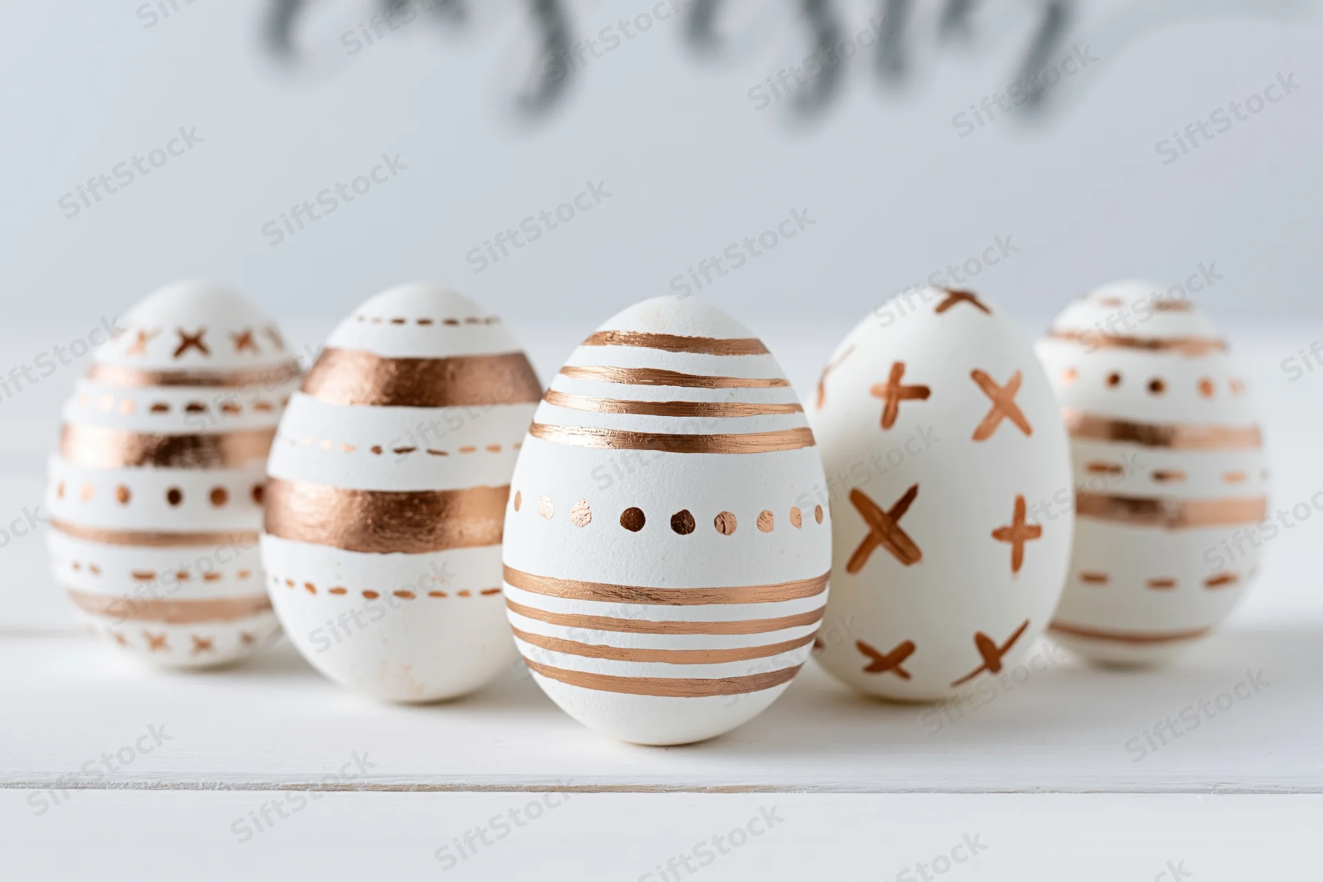 Five white easter eggs decorated with hand-painted copper patterns arranged on a white surface