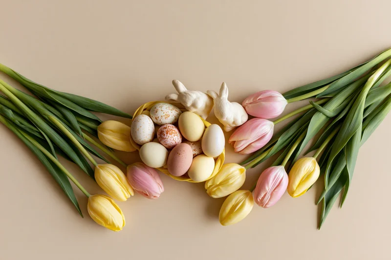 Easter arrangement with tulips and eggs in a basket along the bottom edge of a beige surface