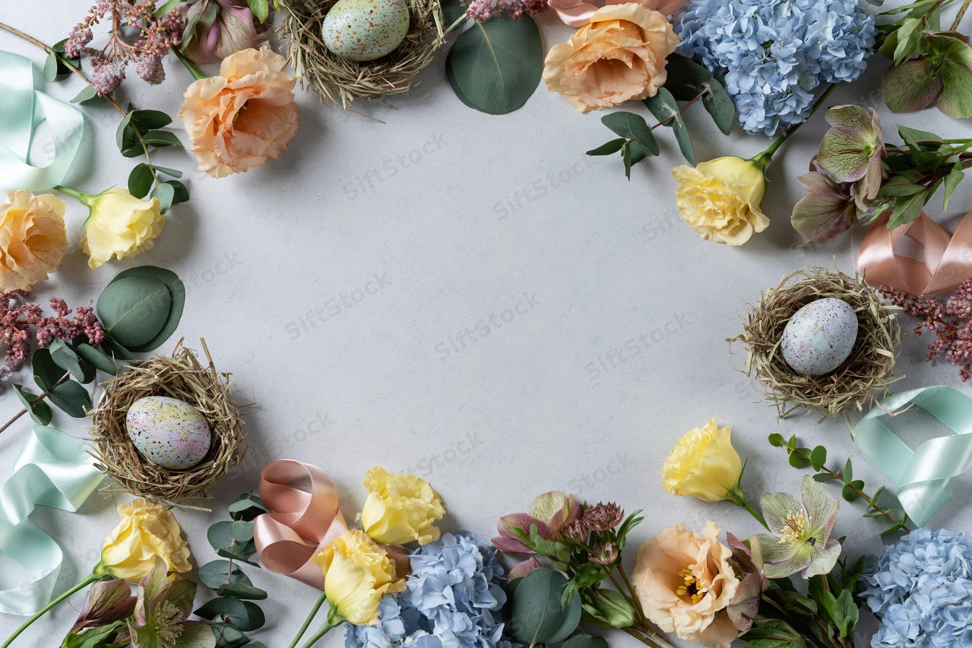 Easter floral arrangement forming a decorative border around a plain surface with nests, eggs, and ribbons