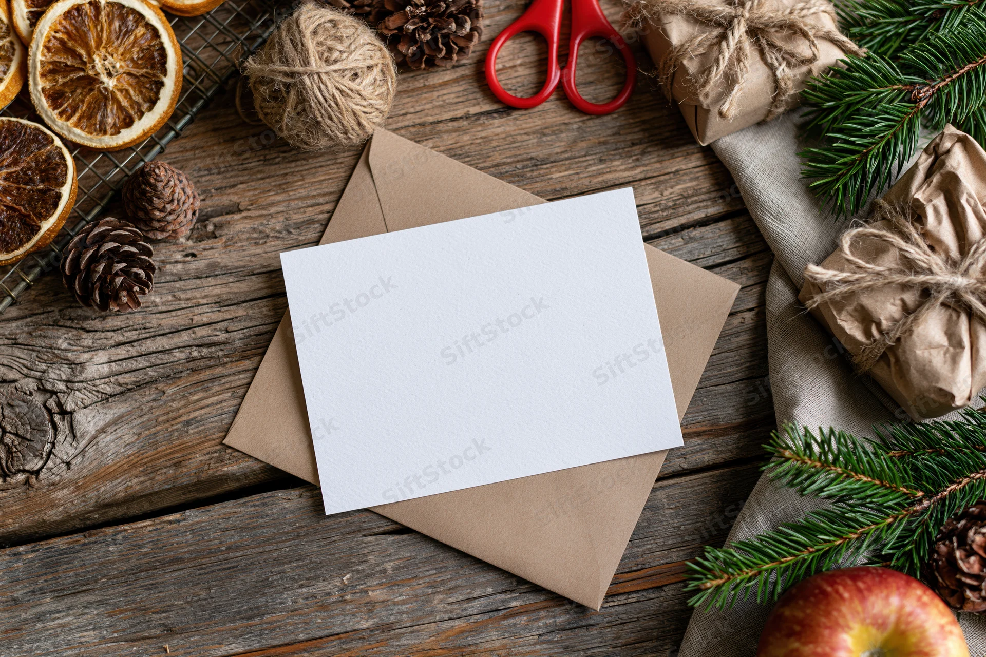 Blank white card on kraft envelope with christmas decorations on wooden surface