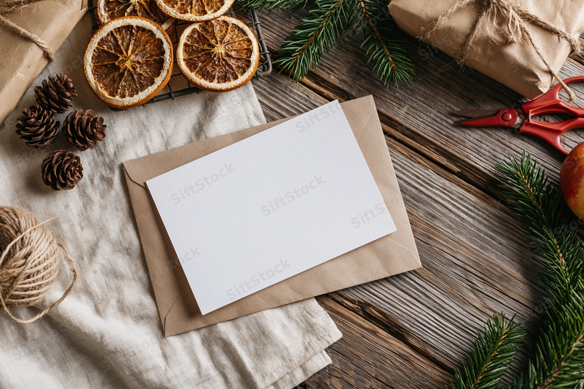 Blank white card on kraft envelope with christmas decor on wooden table