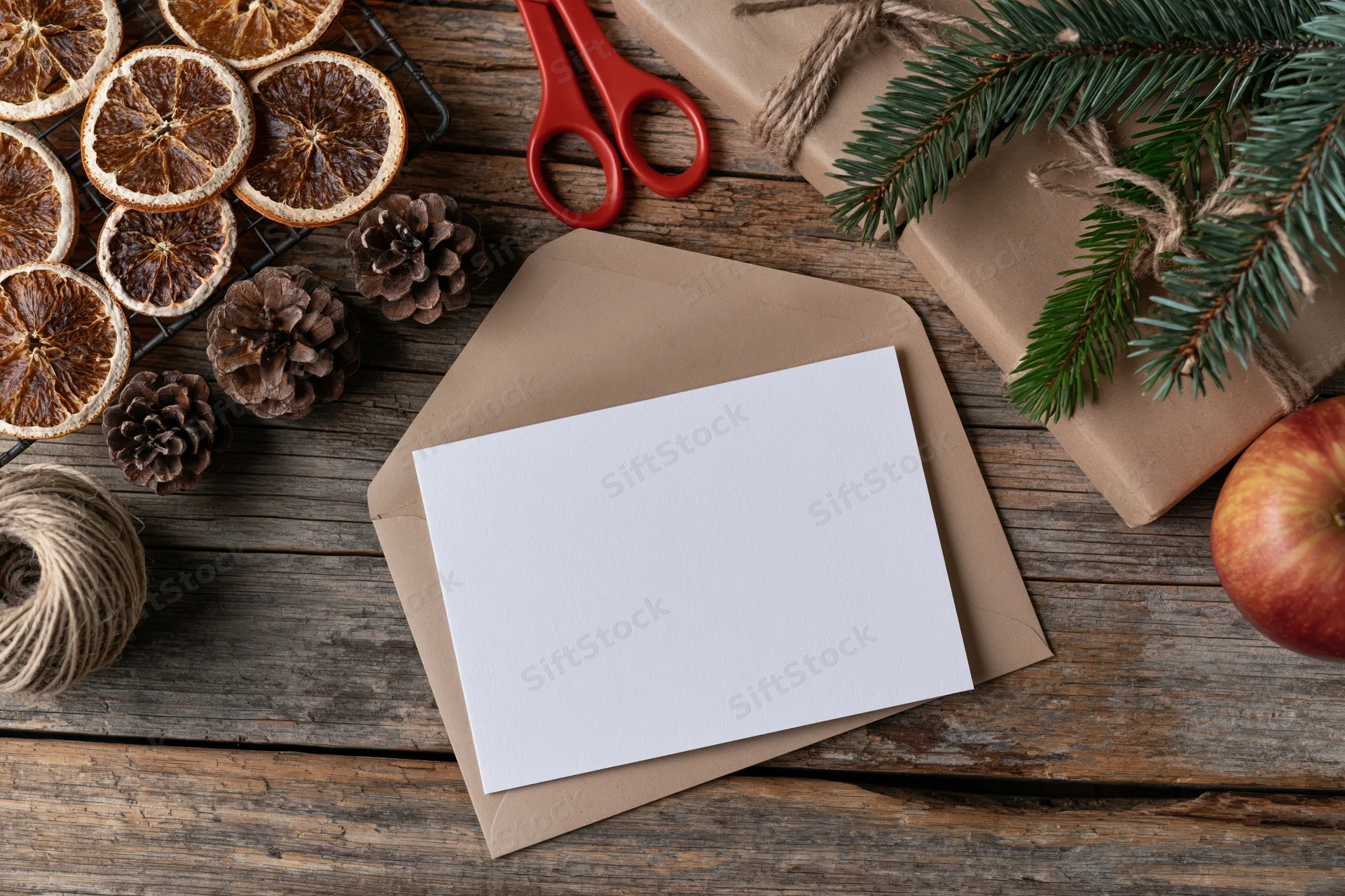 Blank white card on kraft envelope with christmas decorations on wooden table