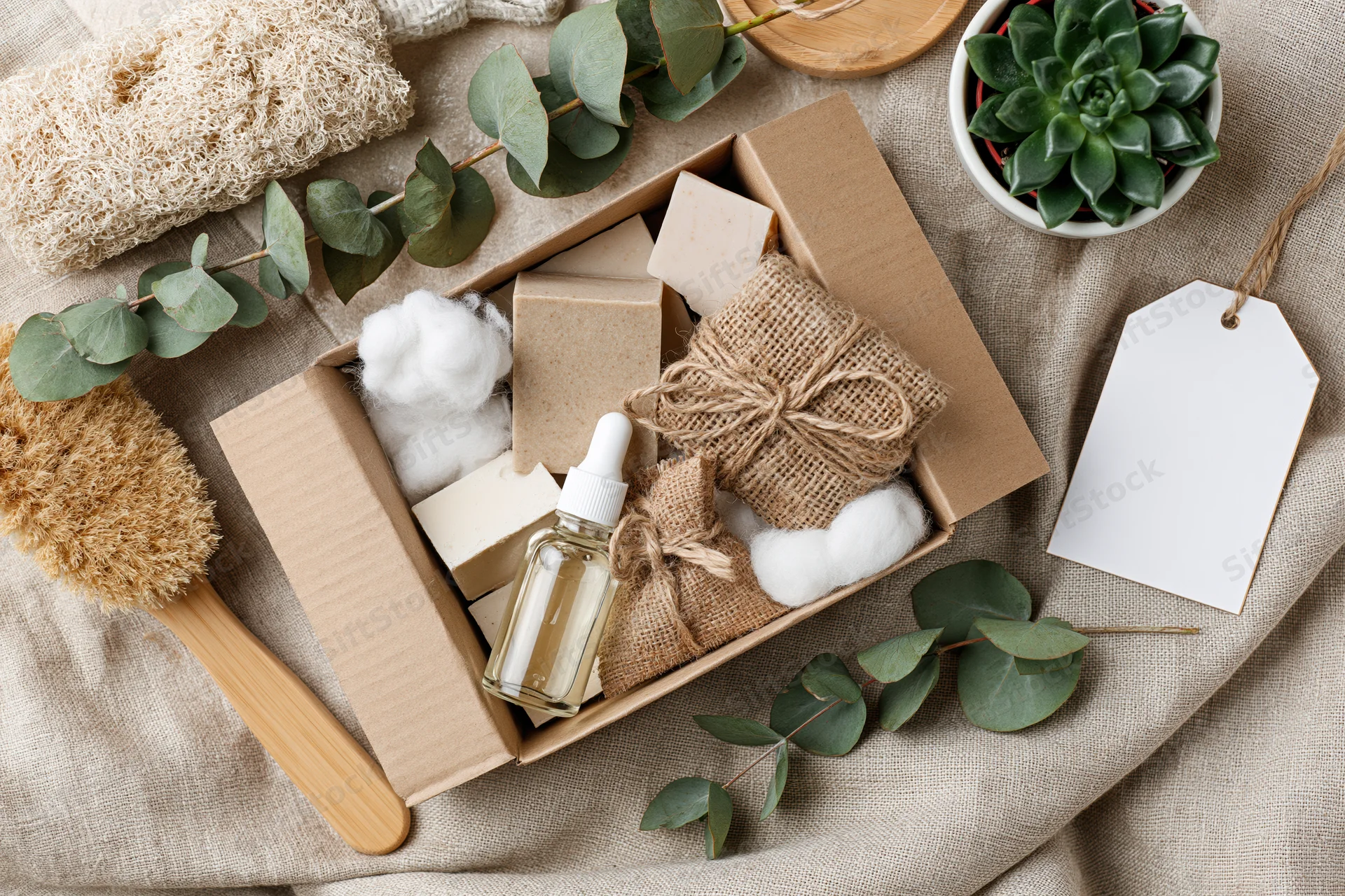 Open kraft cardboard subscription box filled with natural skincare products and greenery on a linen surface
