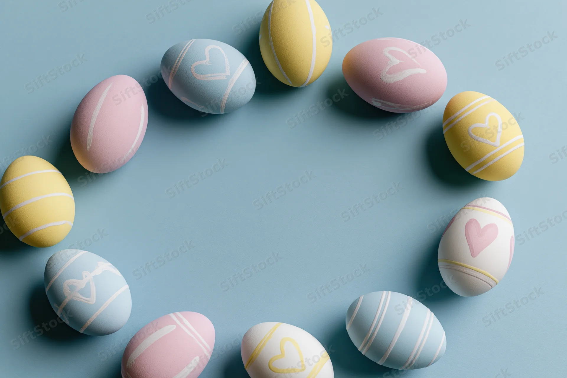 Decorated easter eggs arranged in a loose frame on a blue surface with copyspace in the center