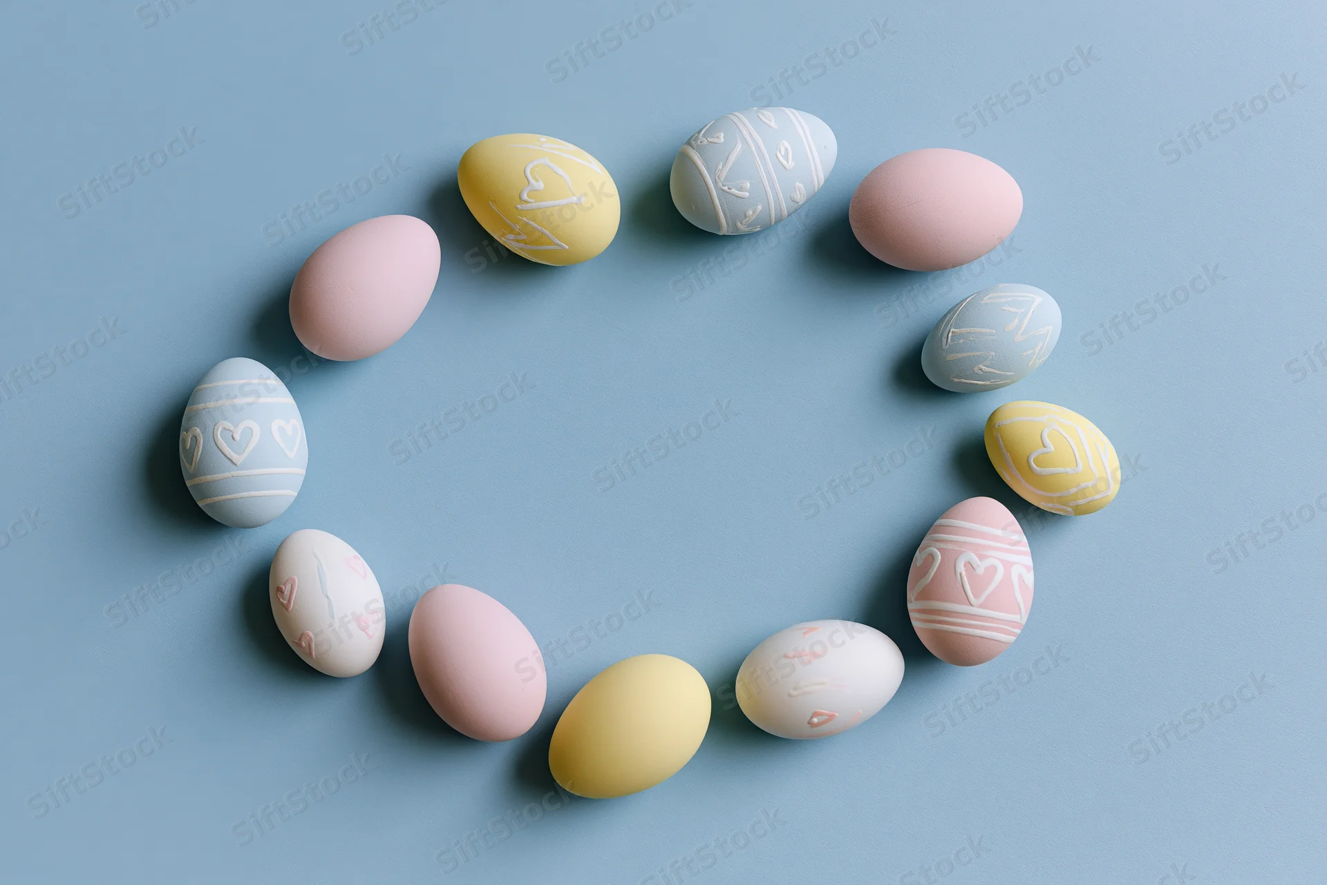 Decorated easter eggs arranged in a loose circular frame on a blue surface