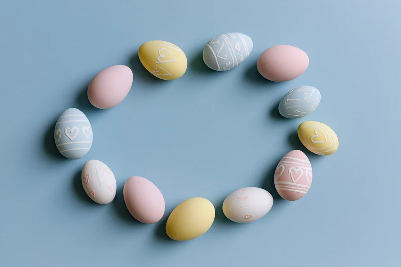 Decorated easter eggs arranged in a loose circular frame on a blue surface