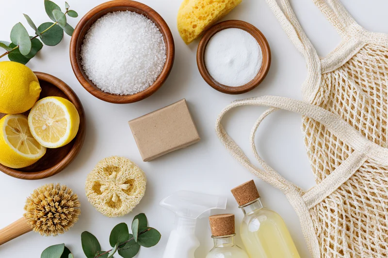 Eco-friendly cleaning supplies arranged in flat lay on white surface