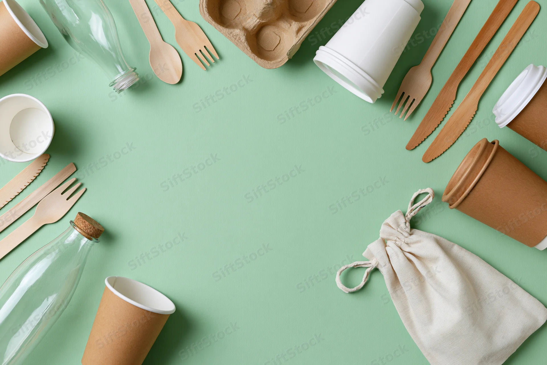 Eco-friendly disposable tableware arranged in a flat lay on a mint green background with copyspace