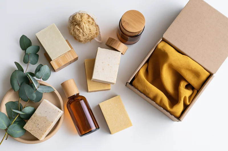 Natural skincare products arranged in flat lay on white surface with eucalyptus and bamboo accessories