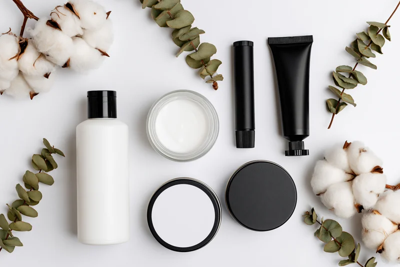 Flat lay of skincare products with cotton and eucalyptus on white background