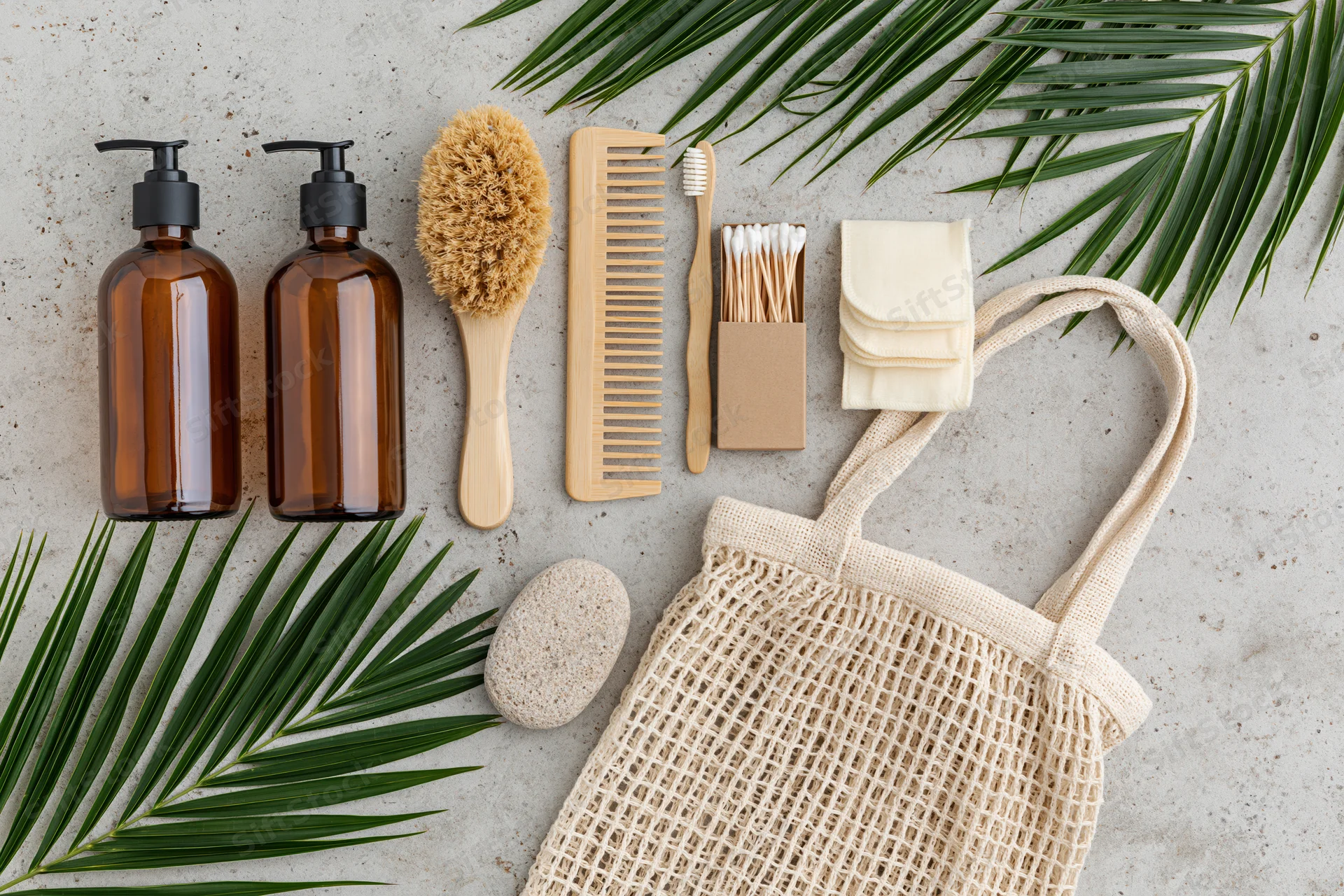 Zero-waste bathroom essentials arranged in flat lay on concrete surface with palm leaves