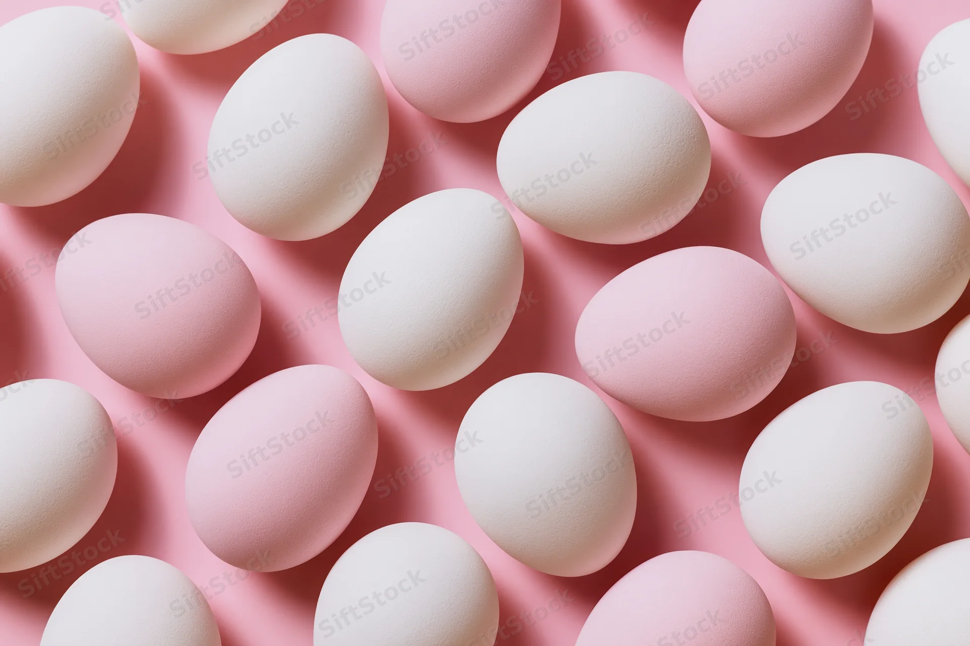 White and pale pink easter eggs arranged in a flat lay overhead pattern on a pink surface