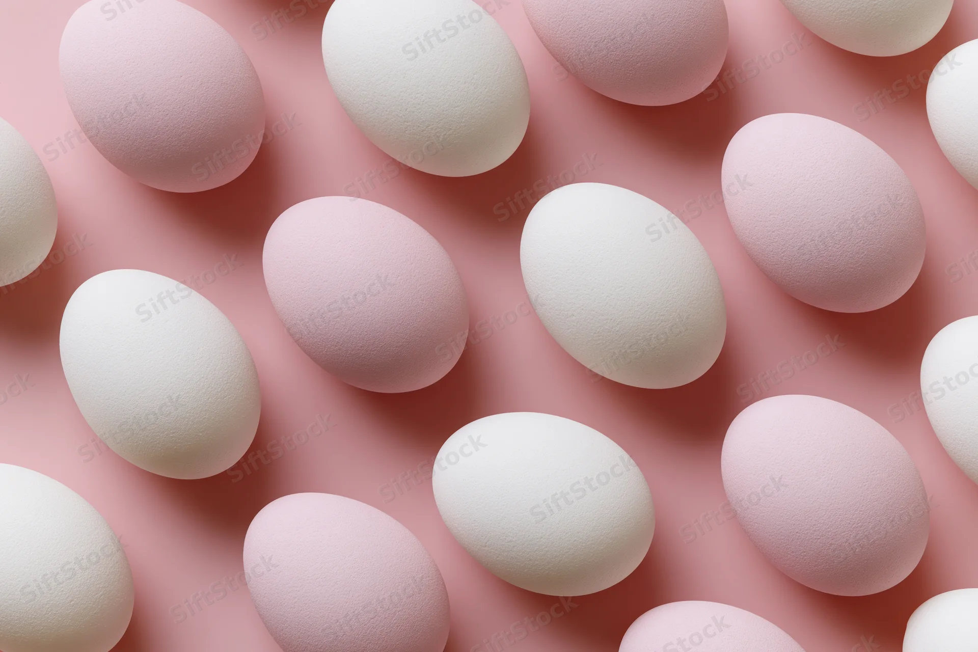 White and pale pink easter eggs arranged in a flat lay overhead composition on a pink surface