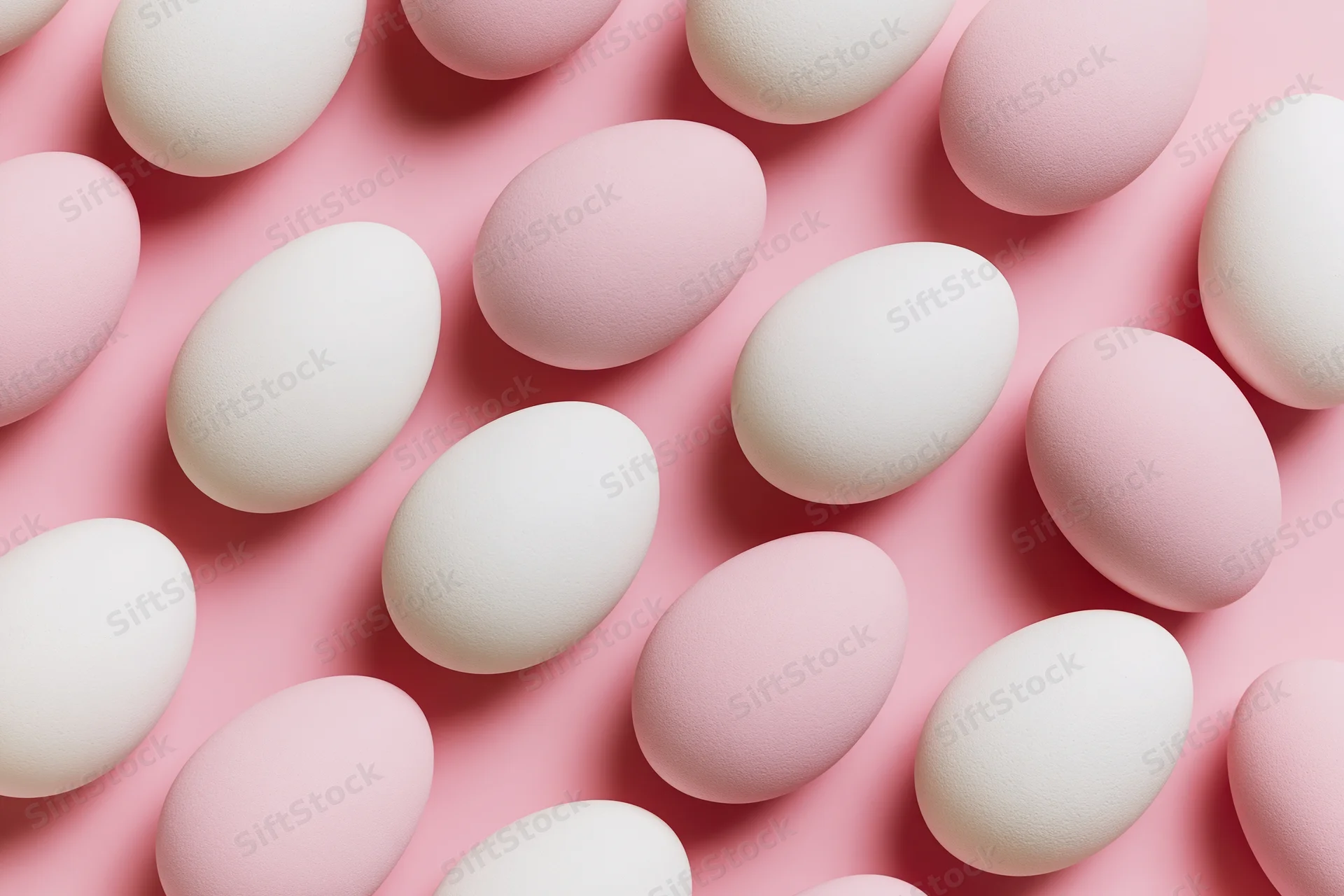White and pale pink easter eggs arranged in flat lay overhead composition on pink surface