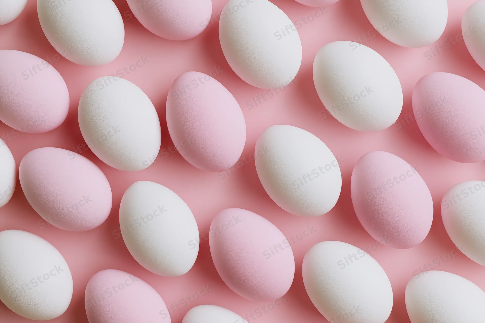 White and pale pink easter eggs arranged in a flat lay overhead pattern on a pink surface
