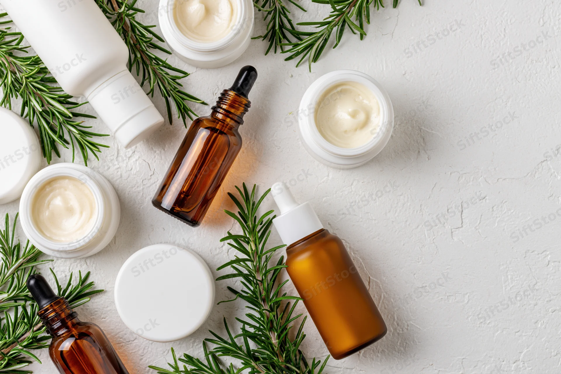 Skincare products with rosemary sprigs arranged on white textured surface