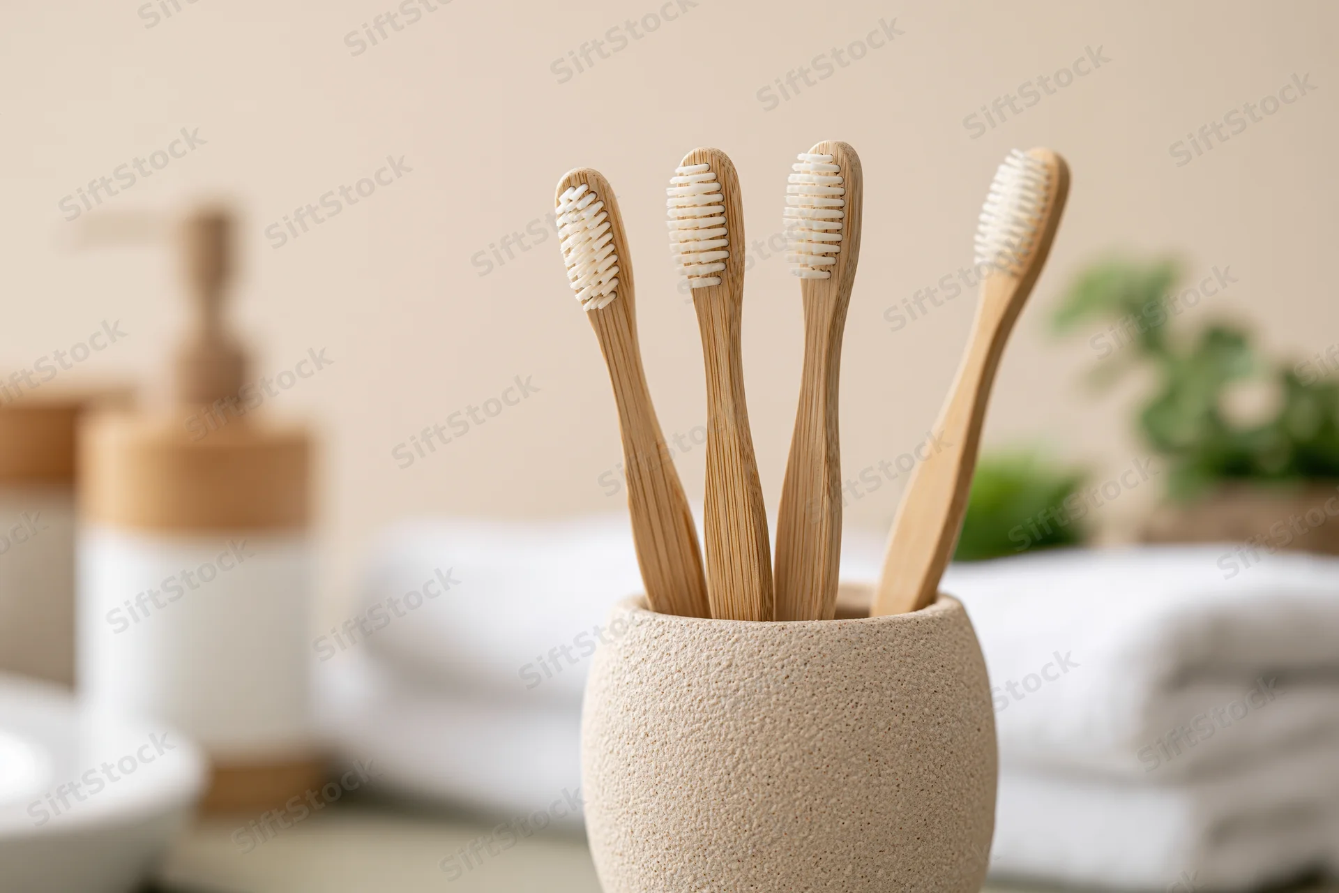Four bamboo toothbrushes with white bristles standing upright in a ceramic holder on a bathroom countertop